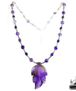 Collier artisanal Dena avec pendentif feuille sculptée en améthyste violette et perles argentées sur fond blanc.