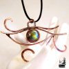 Pendentif artisanal Œil d'Horus en fil de cuivre patiné et cabochon de labradorite aux reflets bleus, talisman de protection fait main.