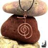 Pendentif en cuivre artisanal représentant le symbole Reiki Cho Ku Rei sur un cordon noir, bijou de guérison énergétique.