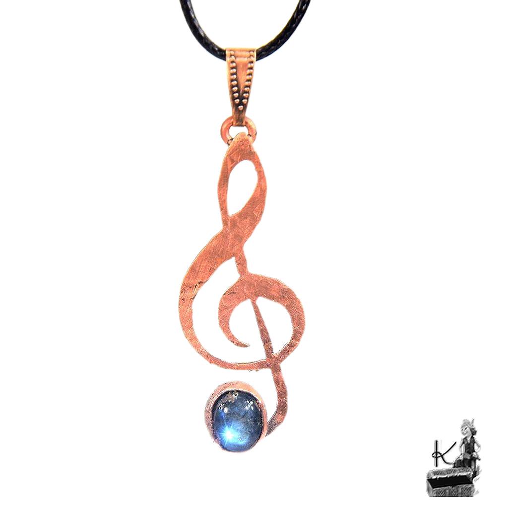 Pendentif artisanal Caden en forme de clé de sol en cuivre avec cabochon de labradorite aux reflets bleutés.