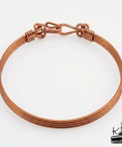 Bracelet jonc artisanal Lucia pour femme en cuivre naturel poli de 19 cm, posé sur un fond inspiré de la nature et de la magie forestière.