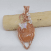 Pendentif artisanal Alara, agate orange entourée de cuivre wire wrapped, motif papillon et fleurs irisées.