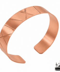 Bracelet large en cuivre martelé de style Viking, bijou artisanal unique posé sur une surface naturelle.