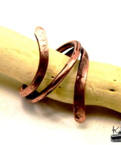 Bague artisanale Hobri en cuivre naturel brut portée sur une main dans une ambiance de forêt mystique.
