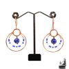 Paire de boucles d'oreilles pendantes artisanales Bega en cuivre naturel et perles de lapis-lazuli sur fond de nature.