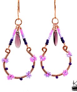Paire de boucles d'oreilles pendantes artisanales Olier en cuivre naturel et perles en verre tchèque sur fond de nature.