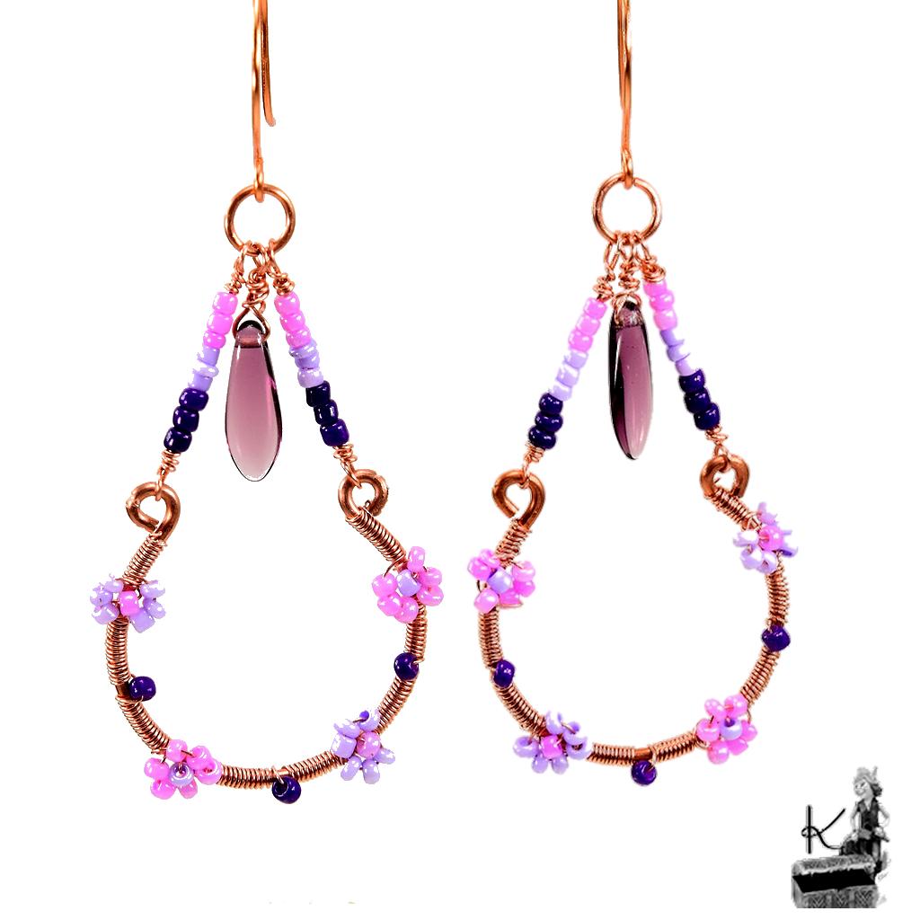 Paire de boucles d'oreilles pendantes artisanales Olier en cuivre naturel et perles en verre tchèque sur fond de nature.