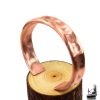 Bracelet manchette Tany artisanal en cuivre martelé naturel de la boutique Le Trésor des Korriganes posé sur fond de mousse et de bois.