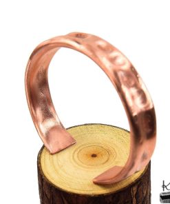 Bracelet manchette Tany artisanal en cuivre martelé naturel de la boutique Le Trésor des Korriganes posé sur fond de mousse et de bois.