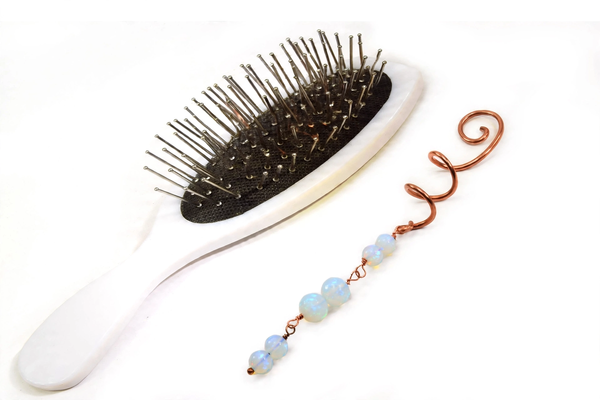 Épingle à cheveux spirale artisanale en cuivre de style celtique ornée de perles d'opalite aux reflets nacrés du Trésor des Korriganes.