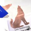 Marque-page loup en cuivre découpé à la main, posé sur un grimoire ouvert près d'une bougie, accessoire de lecture féérique.