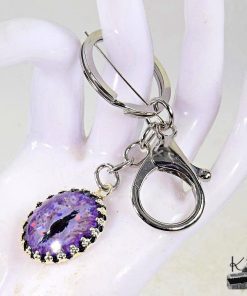 Porte-clé artisanal en métal argenté avec un œil de dragon peint à la main, création magique de la boutique Le Trésor des Korriganes.