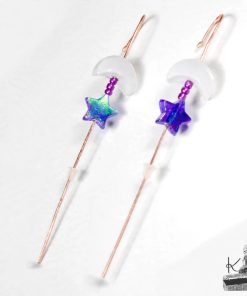 Gros plan sur un bijou d'oreille artisanal Bugadi Heri en cuivre martelé pour oreilles percées, orné d'une lune en pierre de lune et d'une étoile en verre violet