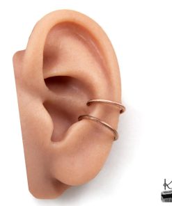 Gros plan sur un ear cuff double onde minimaliste sans perçage en cuivre pur patiné, porté sur le cartilage de l'oreille.